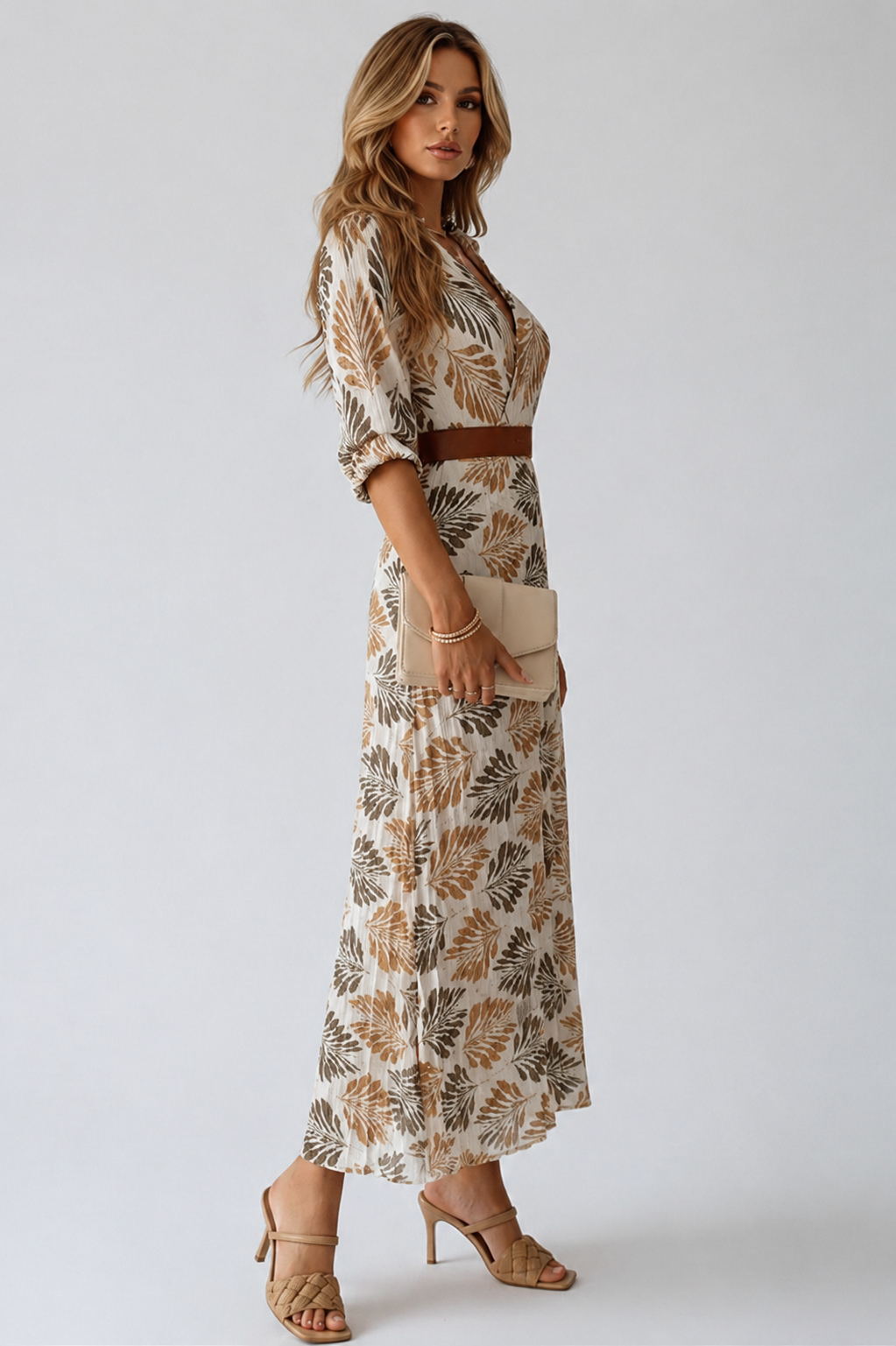 Woman wearing a patterned dress with a belt on a plain background