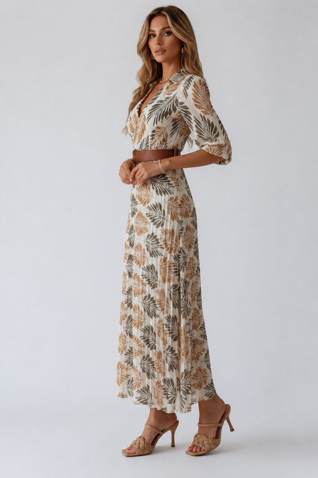 Woman wearing a leaf-patterned dress with a belt on a white background